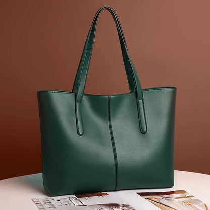 Dark green tote bag angled on a white table with a magazine, brown backdrop 4