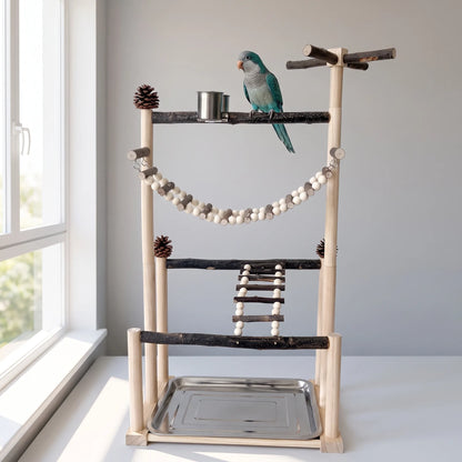 The same bird play stand beside a bright window, with a blue-green parrot perched on the top bark branch next to the steel cup. 2
