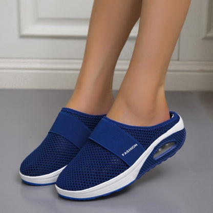 Pair of royal blue mesh slip-on mules with white midsole, worn indoors by a model 5