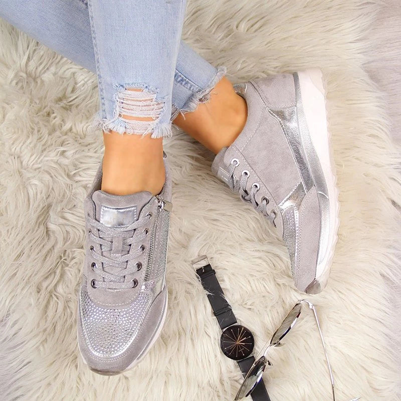 Top-down view of grey trainers worn on a fluffy cream rug, with a black watch and sunglasses beside them. 6