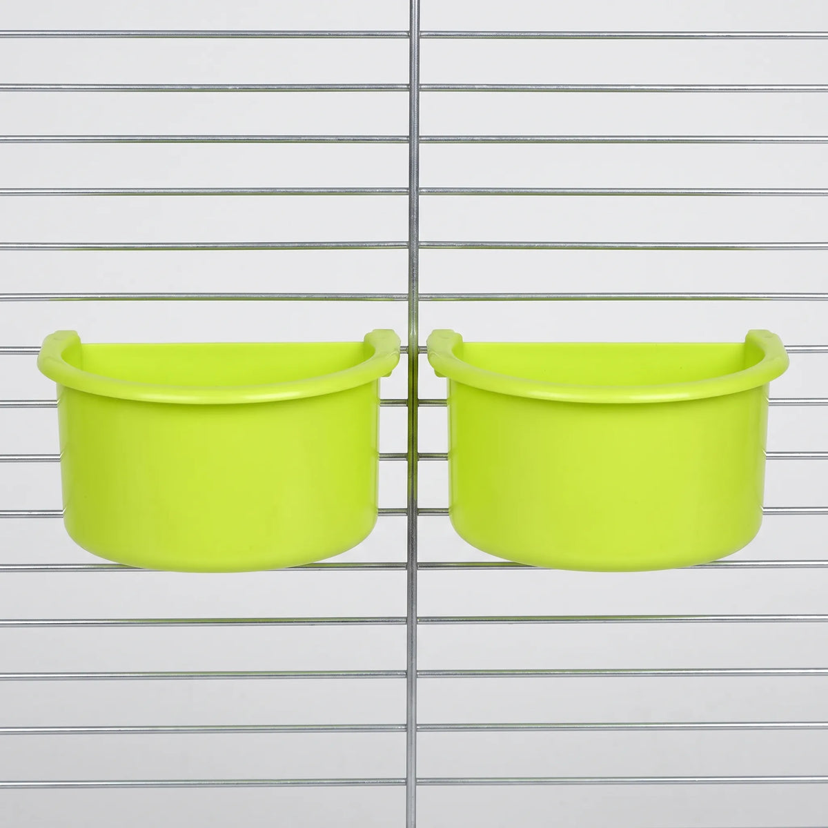 Two green half-round bowls hung side by side on the wire bars of a metal cage. 4