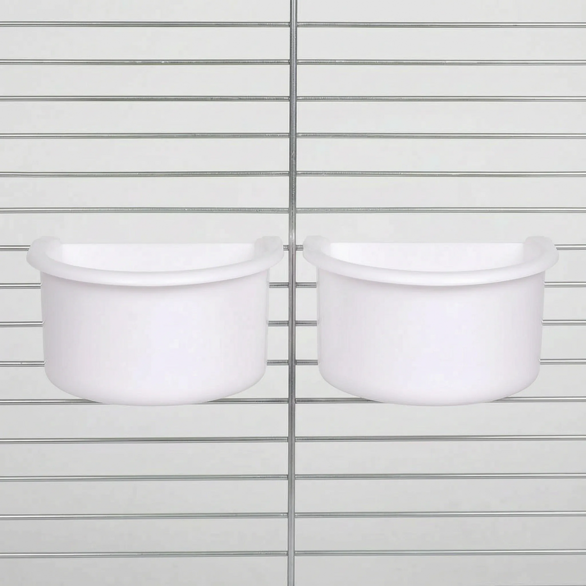 Two white half-round plastic bowls hung side by side on the wire bars of a metal cage. 5