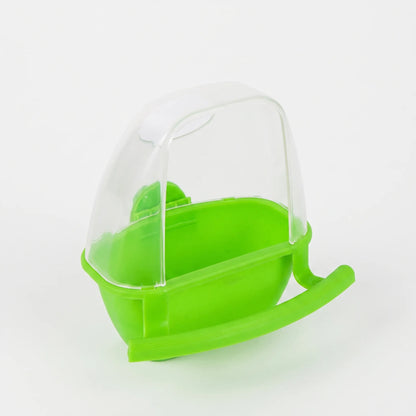 Green plastic feeder with a clear hood and curved perch, shown at an angle on a plain light background. 1