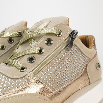 Close-up of a beige trainer showing gold metallic laces, metal eyelets, side zip and rows of small crystal studs. 8
