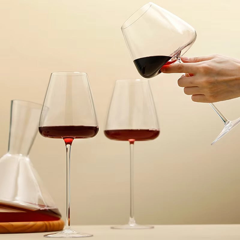 One glass tilted in a hand while two upright red wine glasses and a decanter stand nearby 9