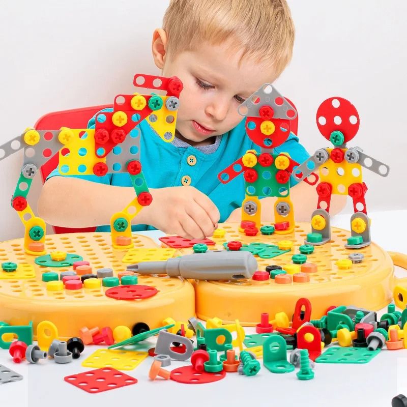Boy sits at a table building colourful robot figures from plastic plates, bolts and nuts on the yellow pegboard case. 2