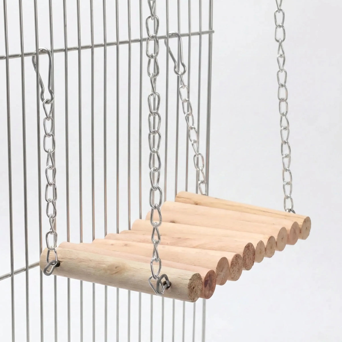 Wooden rung bridge hanging from metal chains and clip hooks against the bars of a wire cage, seen from a low angle. 1