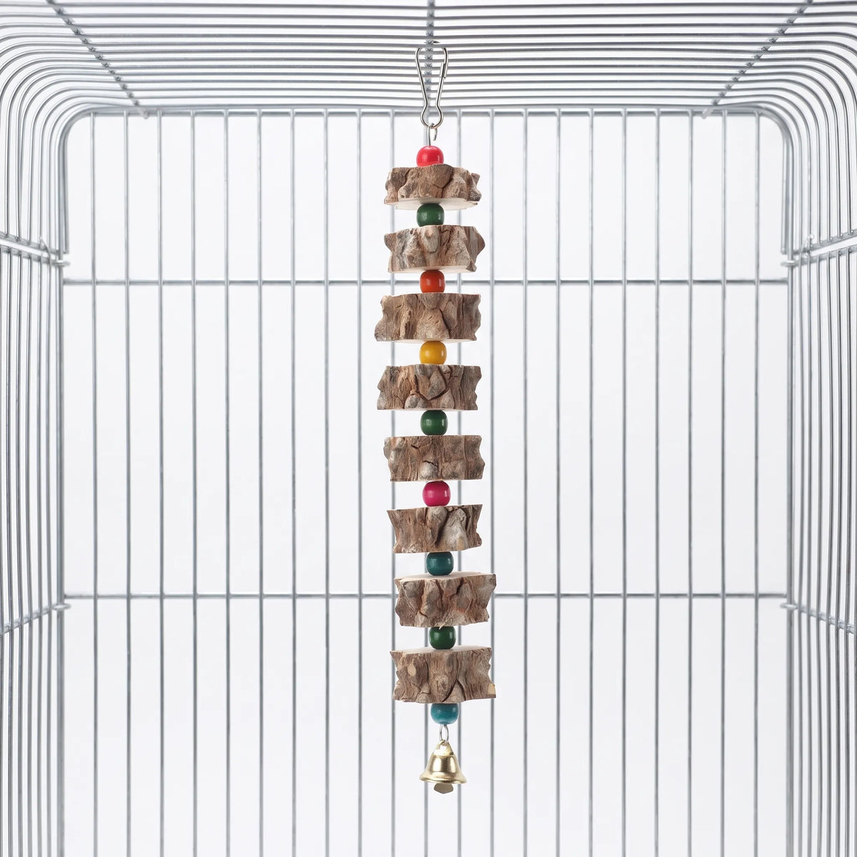 Toy hanging from a metal hook inside an empty wire cage, with bark-edged wooden slices, coloured beads and a small gold bell. 1