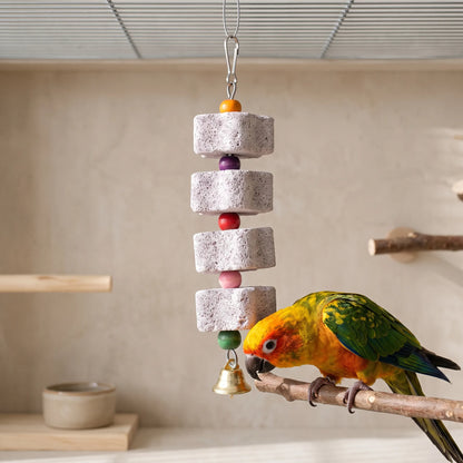 The same four-block pumice toy hanging in a cage while a sun conure perches on a branch beside it, beak close to the bottom block. 2