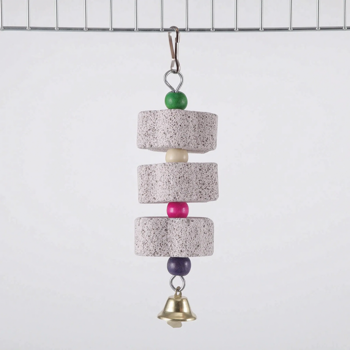 Three round pumice discs spaced by cream, pink and purple beads, with a green bead at the top and a brass bell, hanging from cage wire. 7