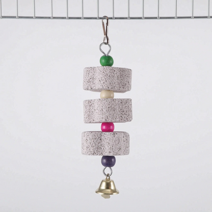 Three round pumice discs spaced by cream, pink and purple beads, with a green bead at the top and a brass bell, hanging from cage wire. 7