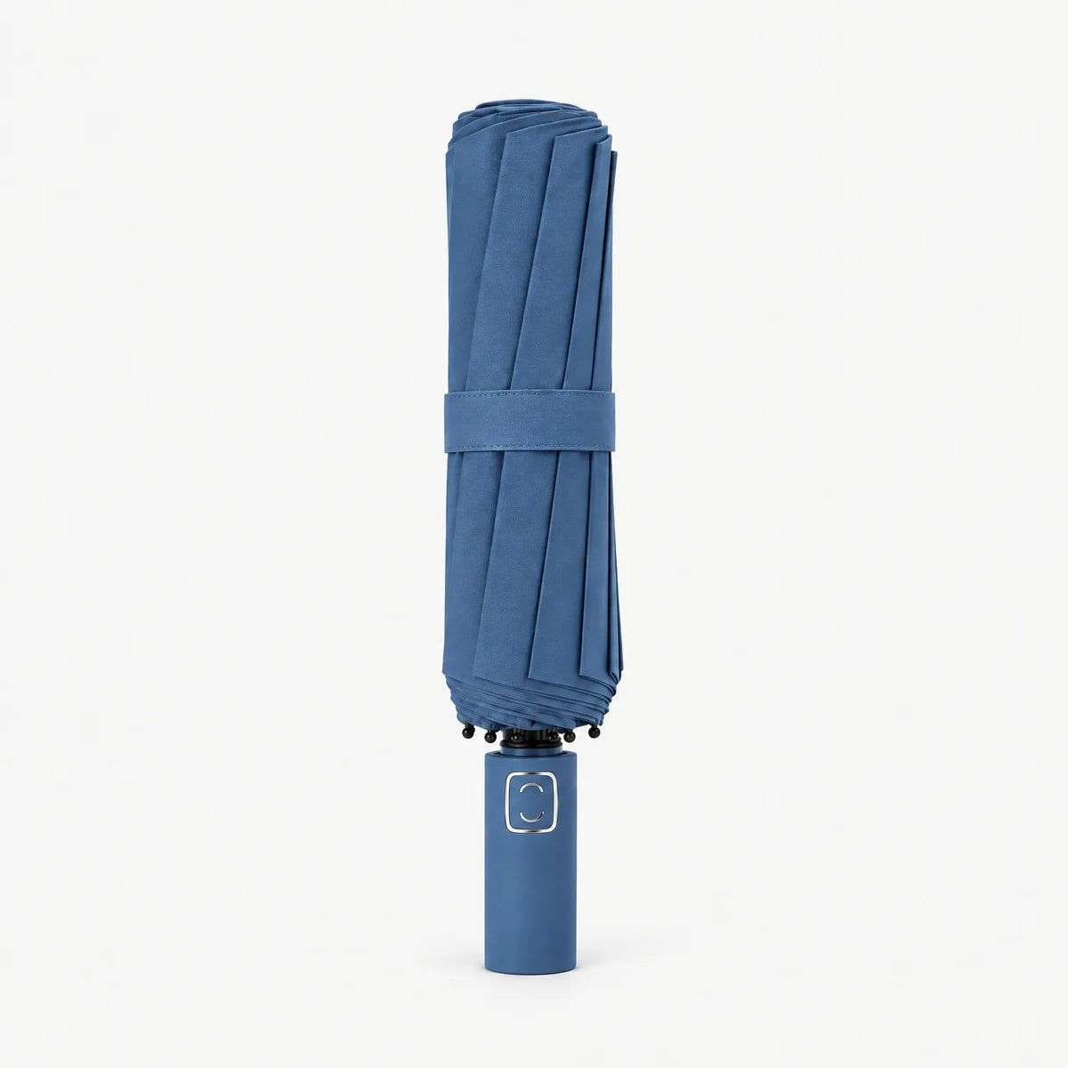 Folded denim blue umbrella standing handle-down on a white background, with a matching strap and a metallic square on the handle. 11