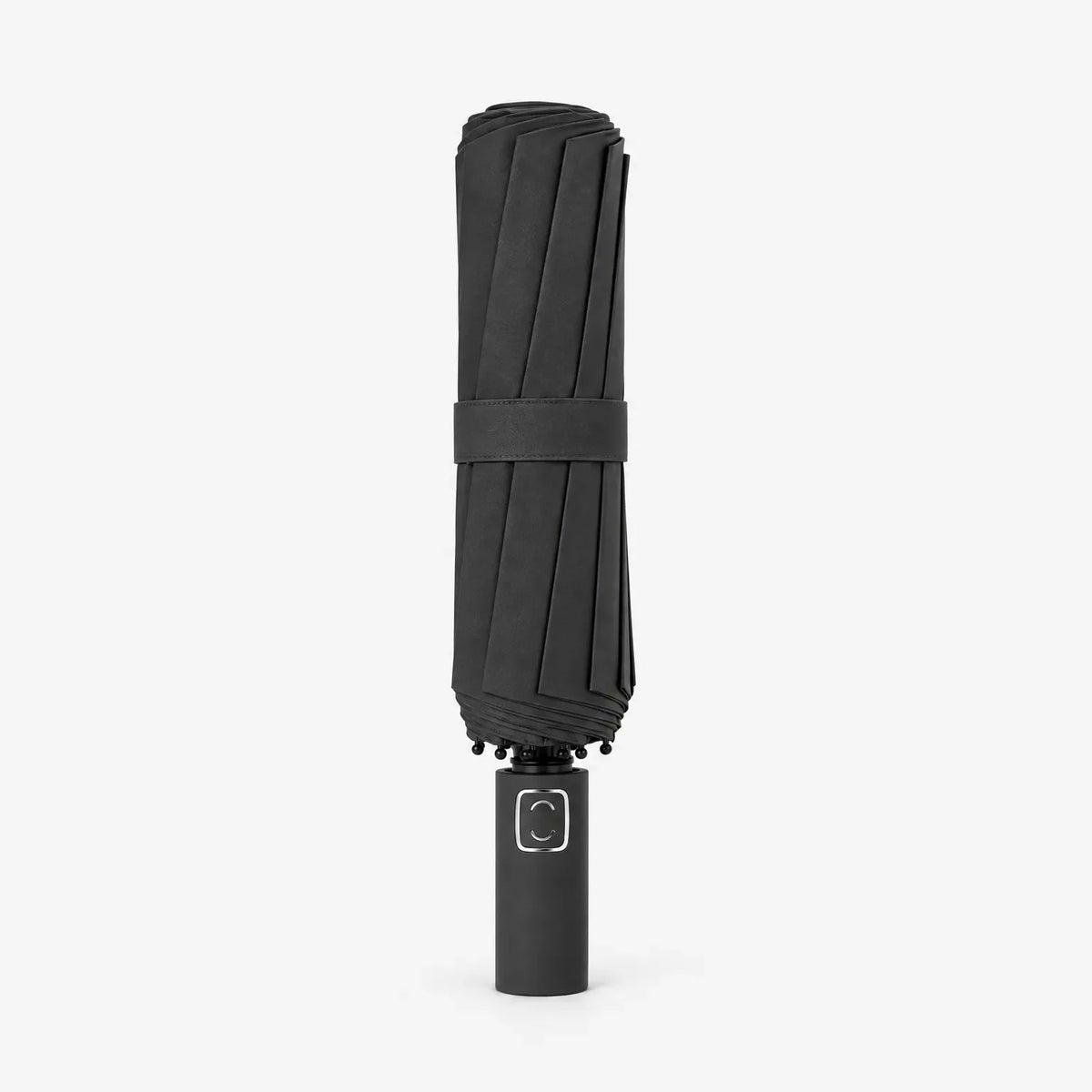 Folded black umbrella standing upright on a white background, with a fabric strap around the canopy and a plain handle. 2