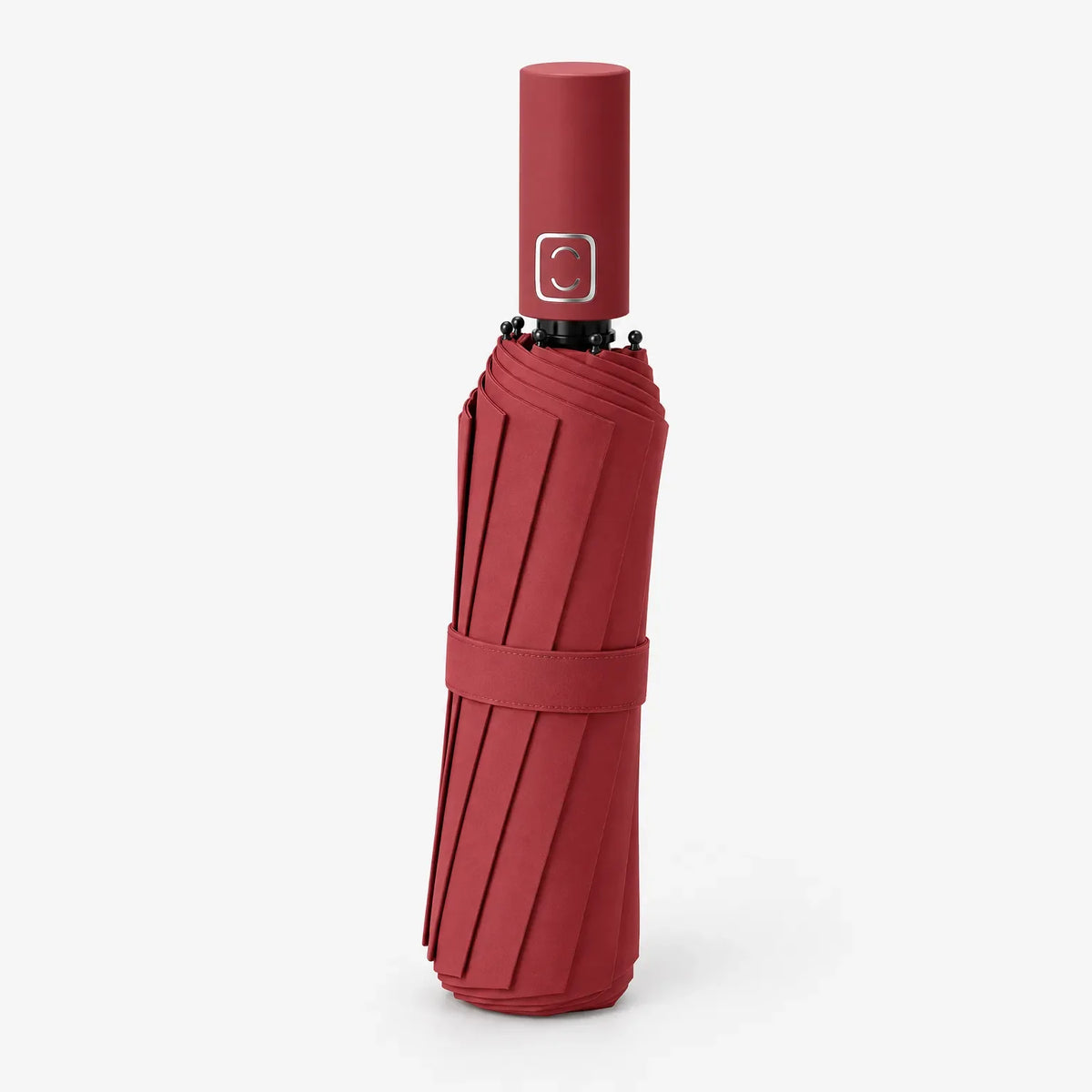 Folded red umbrella standing handle-up on a white background, angled slightly, with a fabric strap and black rib tips visible. 4