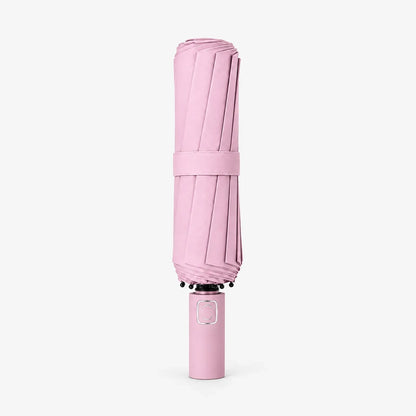 Folded pale pink umbrella standing handle-down on a white background, wrapped with a matching fabric strap around the canopy. 7