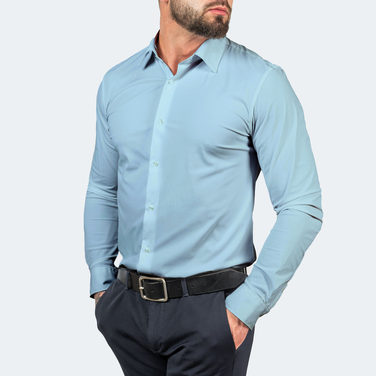 Light blue shirt worn buttoned by a model with hands in the pockets of dark trousers 12