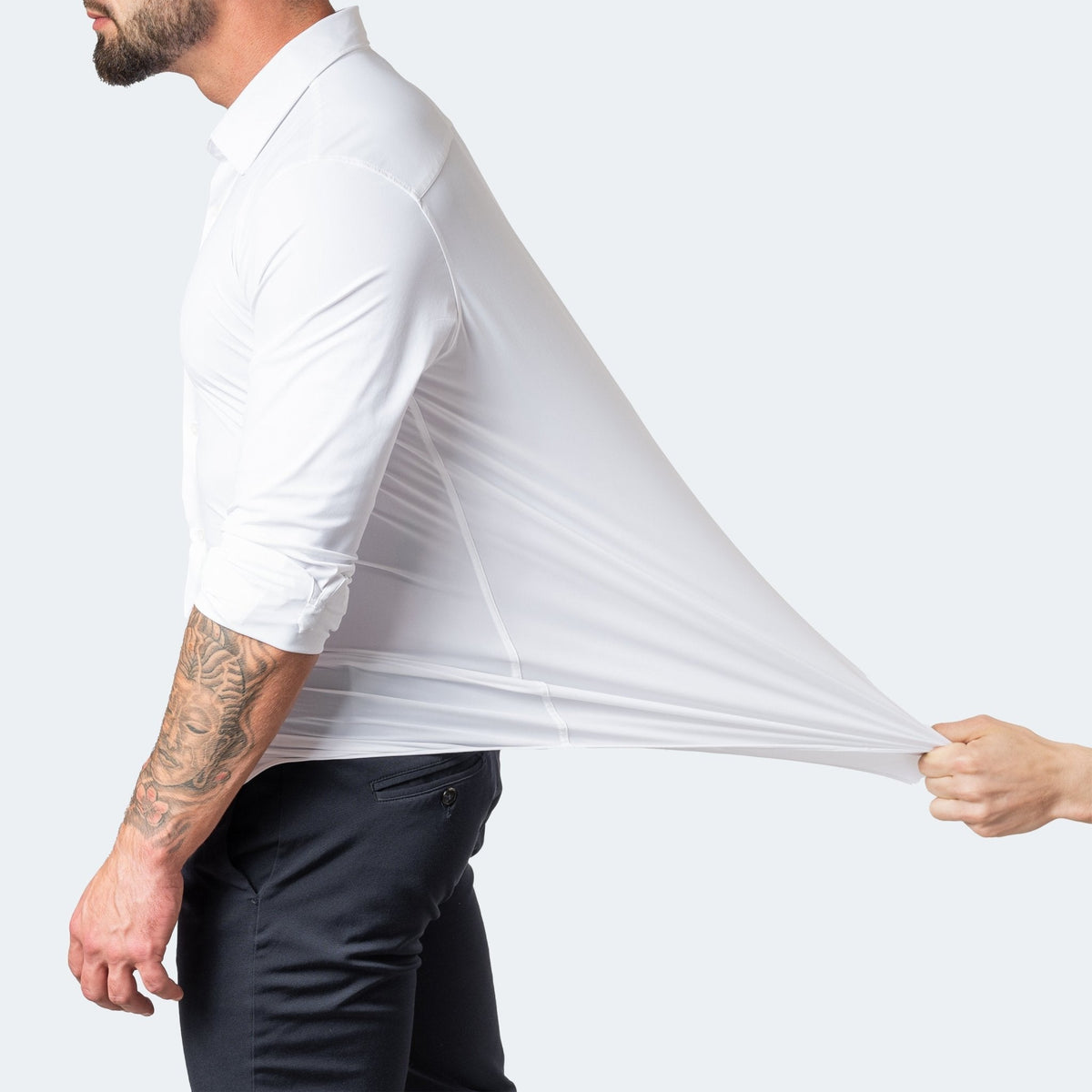 White shirt with sleeves rolled up, a hand pulling the back fabric far out to show stretch 3