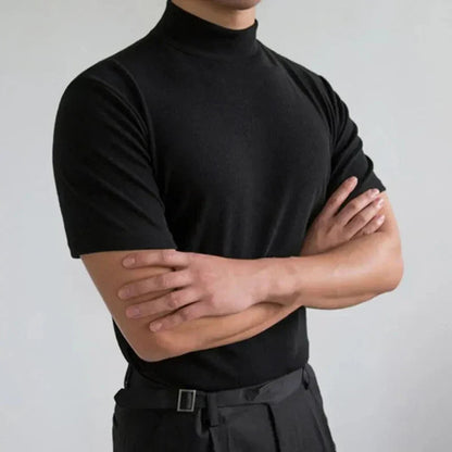 Same black high-neck t-shirt worn with arms crossed against a light grey backdrop, showing the fitted short sleeves and neckline. 2