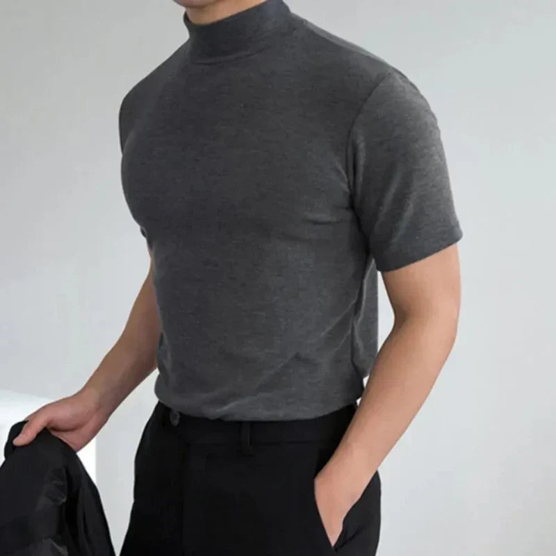 Model wearing the dark grey high-neck t-shirt with one hand in a trouser pocket and a jacket held in the other. 3