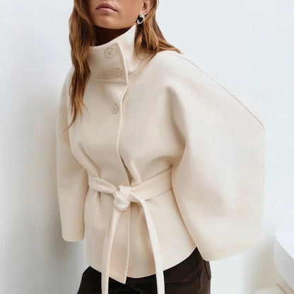 Model wearing the cream cape jacket with a knotted belt, dark trousers and silver earrings 3