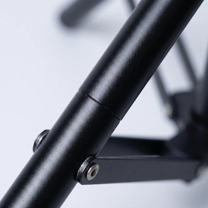Close-up of a matt black tripod leg showing the tube joint and a metal screw fixing the folding brace. 3