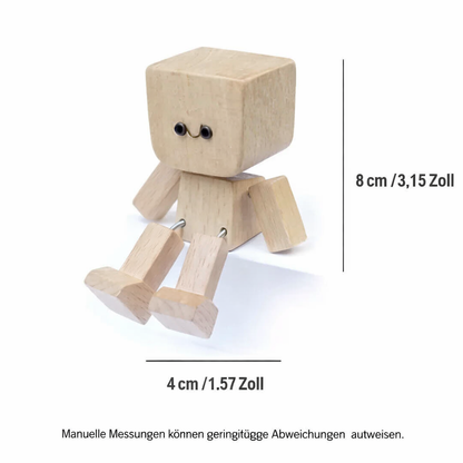Seated wooden figure on white with dimension lines marking its height and width, showing the spring-jointed legs and arms. 8