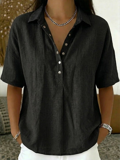 Model wearing the short-sleeved blouse in black, with metal snap buttons and a chain necklace 6