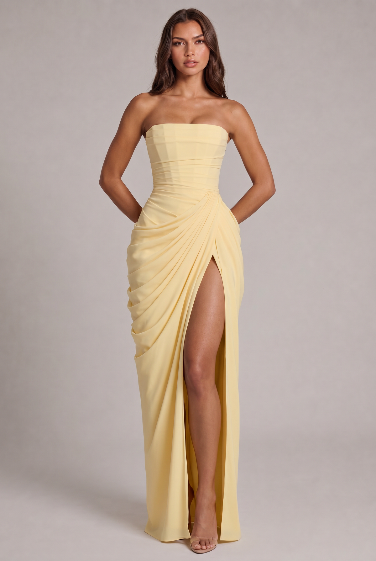 Model facing the camera in the pale yellow strapless maxi dress with draped skirt and high slit 1