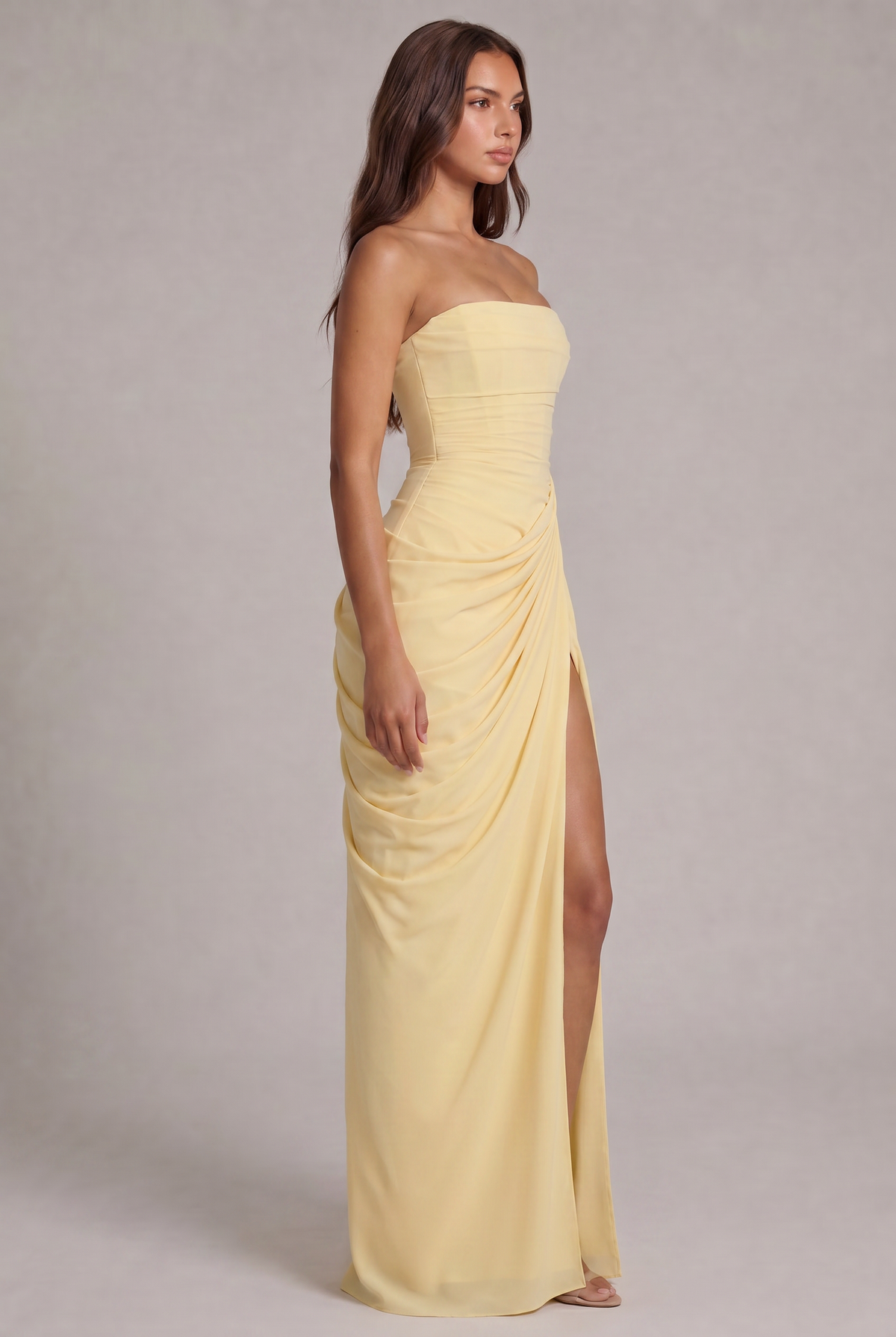 Side view of the pale yellow strapless dress showing the draped skirt and thigh-high slit 3