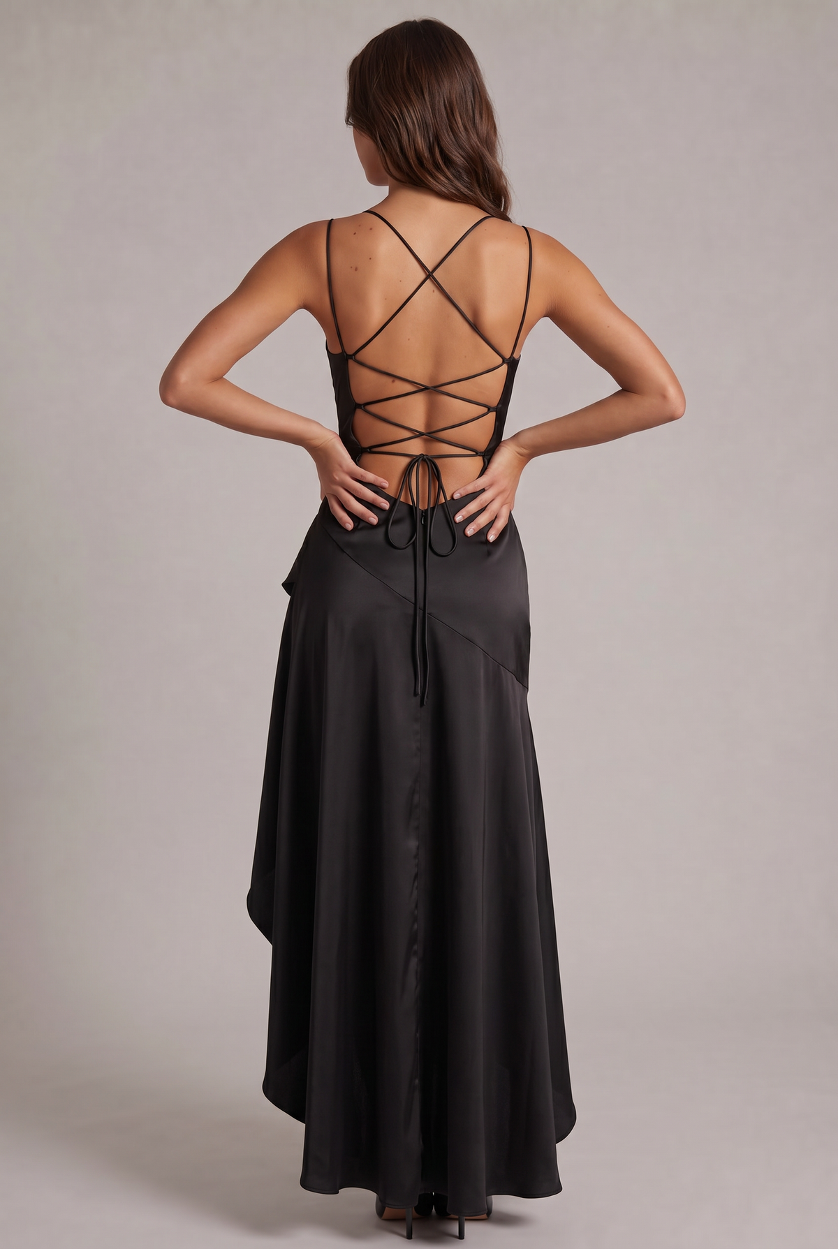 Back view of the black dress with crossed lace-up straps over an open back and a tie at the base. 12