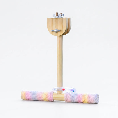 Wooden T-shaped swing perch with a pastel rope-wrapped bar, clear bead ring and wing-nut clamp, shown on a plain white background. 1