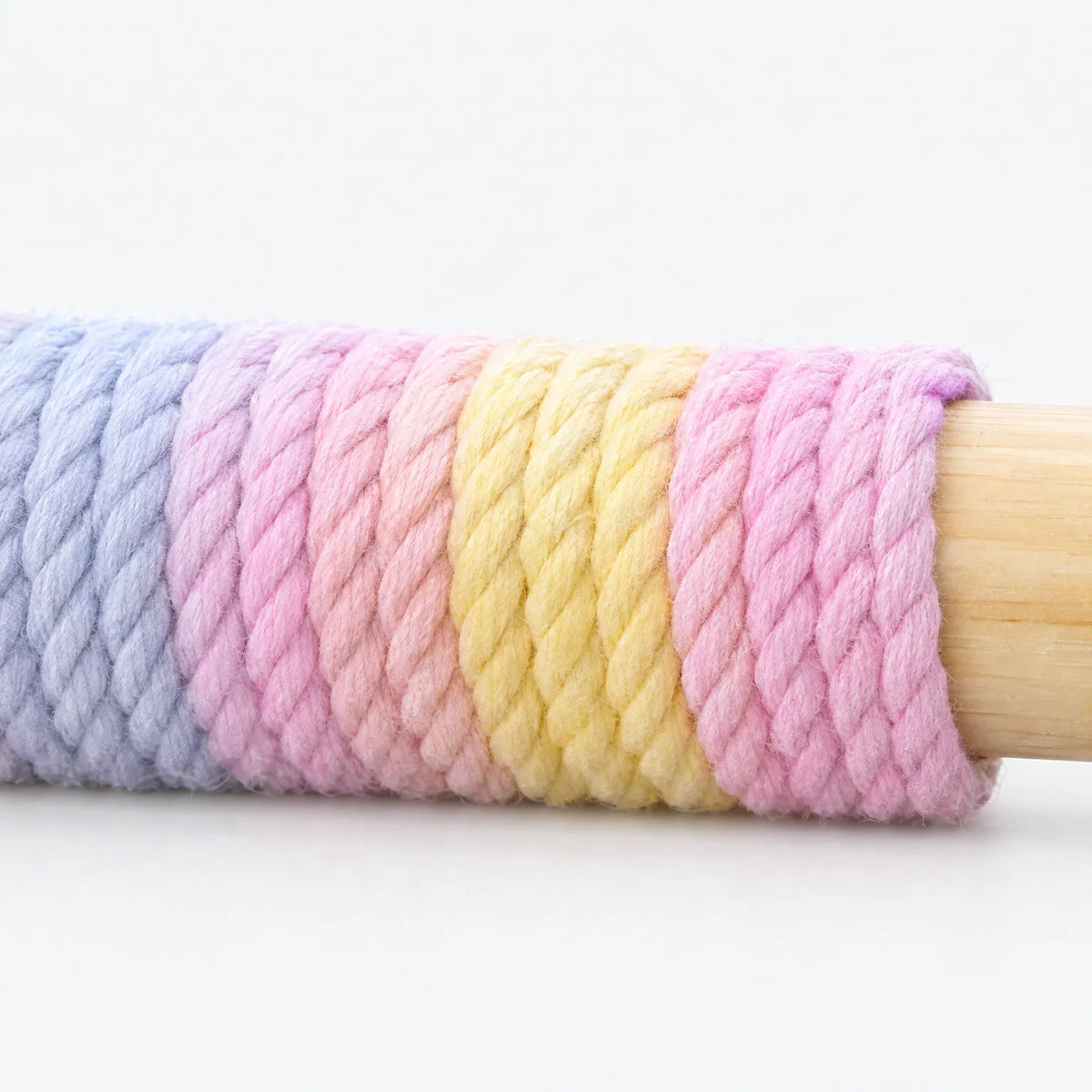 Close-up of the thick twisted rope wrapping in pastel blue, pink and yellow stripes around the bare wooden perch bar. 3