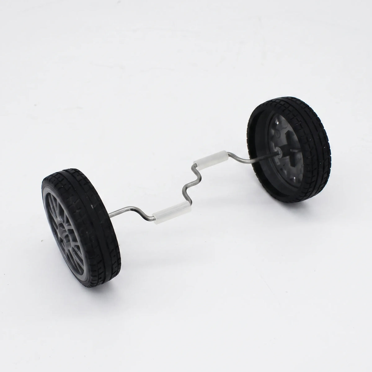 Pair of black rubber-tyred wheels joined by a bent metal axle with white grip sleeves, shown on a plain white background. 1