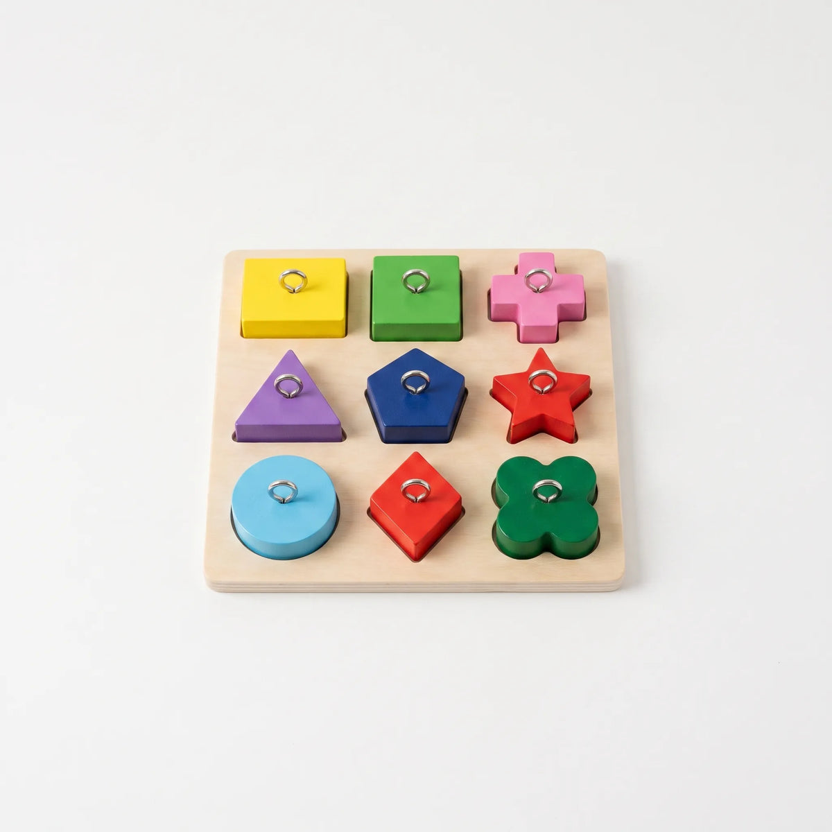 Wooden board with nine colourful shaped blocks, each with a metal ring on top, seen from above on a white background. 1