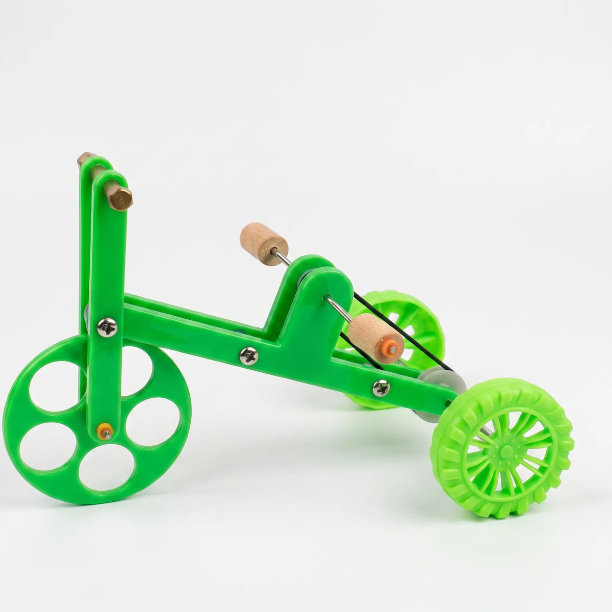 Side view of a green plastic tricycle-style bird toy with wooden foot perches, a drive band and a perforated front wheel, on white. 1