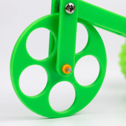 Close-up of the green perforated front wheel, showing its round cut-outs, a metal screw and a small yellow axle cap. 3