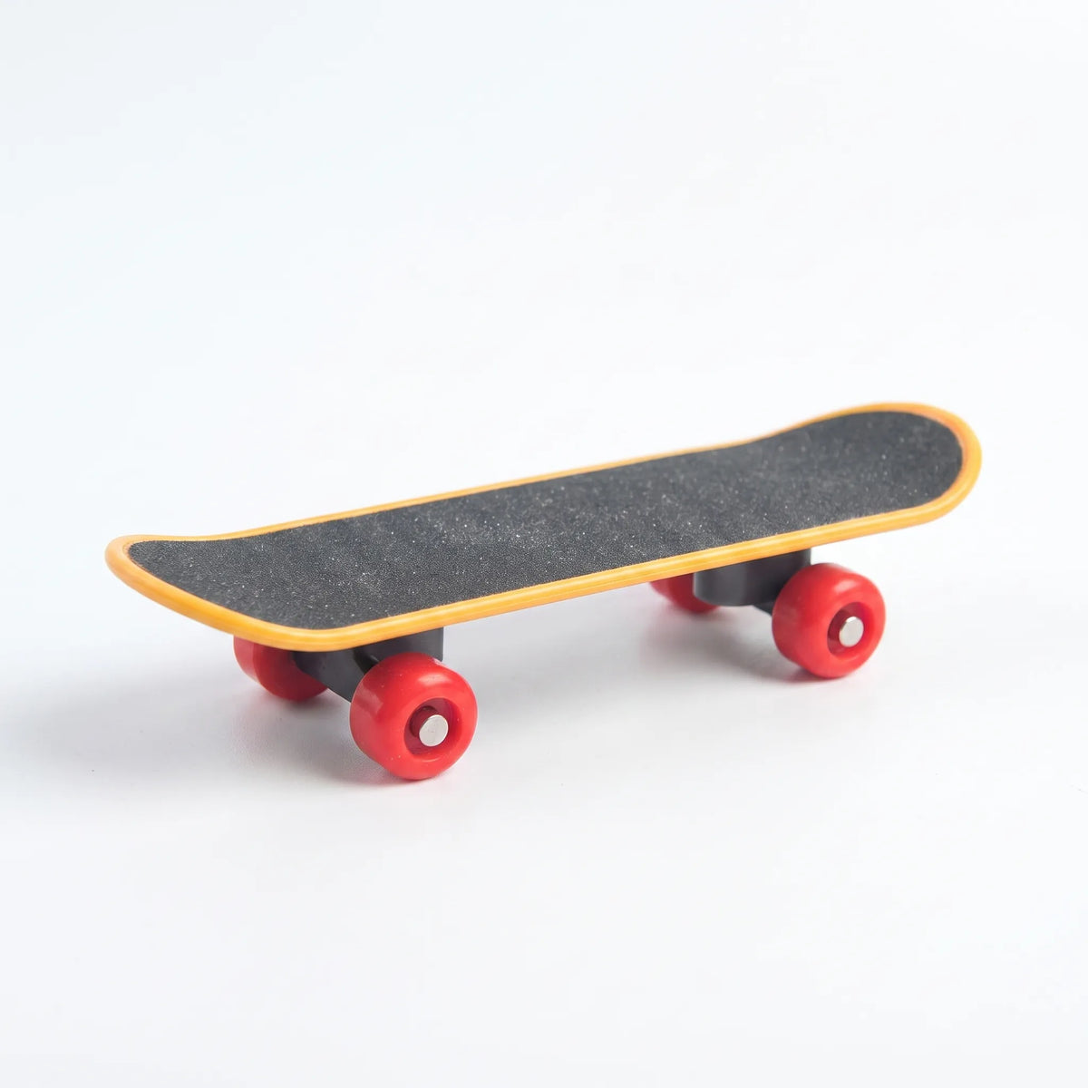 Miniature skateboard toy with a gritty black deck, yellow edging and red wheels, shown on a plain white background. 1