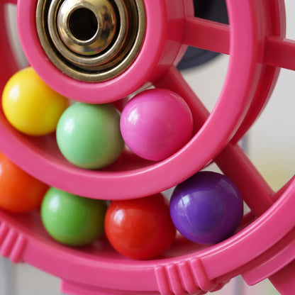 Close-up of the pink wheel's brass-coloured bearing hub and glossy yellow, green, pink, red and purple balls inside the ring. 3