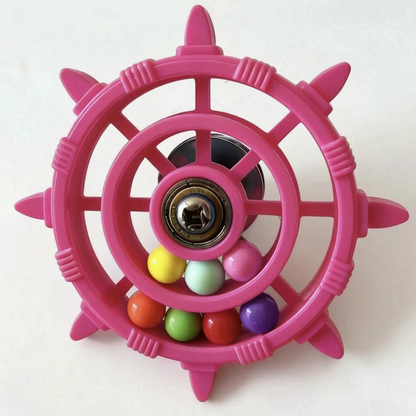 Pink wheel toy seen slightly from the side, showing the dark suction-style mount behind the hub and the loose balls below. 4