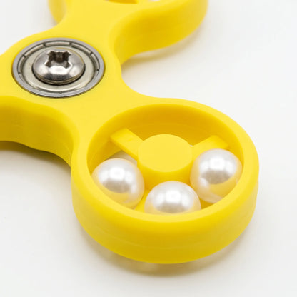 Close-up of one ring of the yellow spinner, showing three glossy white beads, the central hub and the metal bearing screw. 4