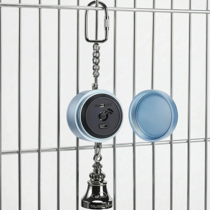 Blue version hanging from a cage bar with its screw-off back cover detached beside it, revealing the black panel with switch, record button and charging port. 5