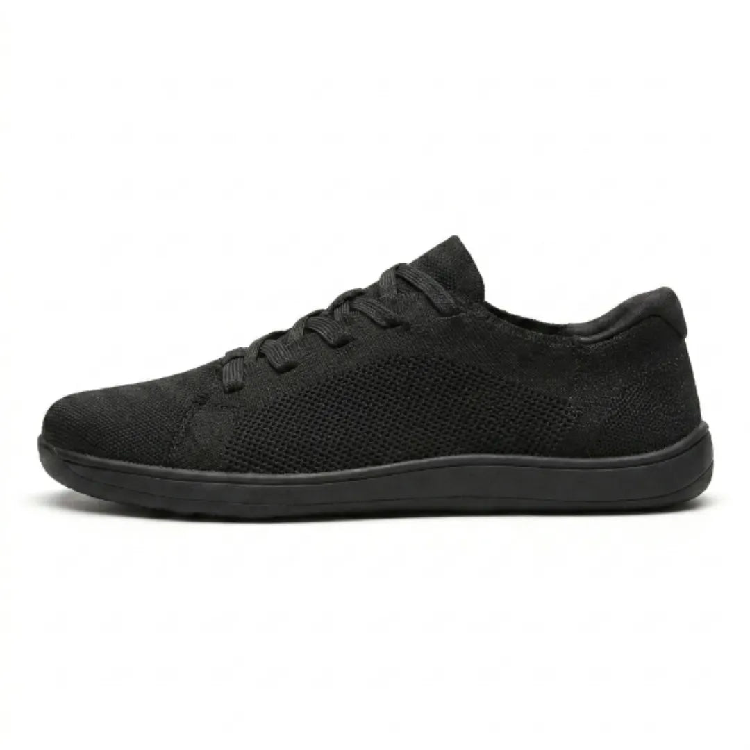 Side view of a black lace-up knit trainer with a perforated mesh panel and a flat black sole. 10