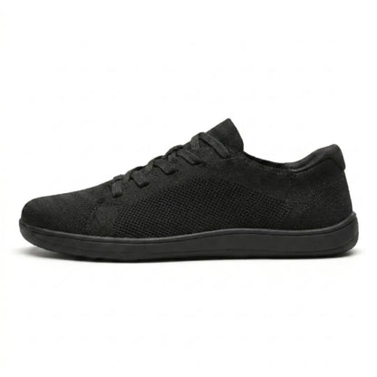 Side view of a black lace-up knit trainer with a perforated mesh panel and a flat black sole. 10