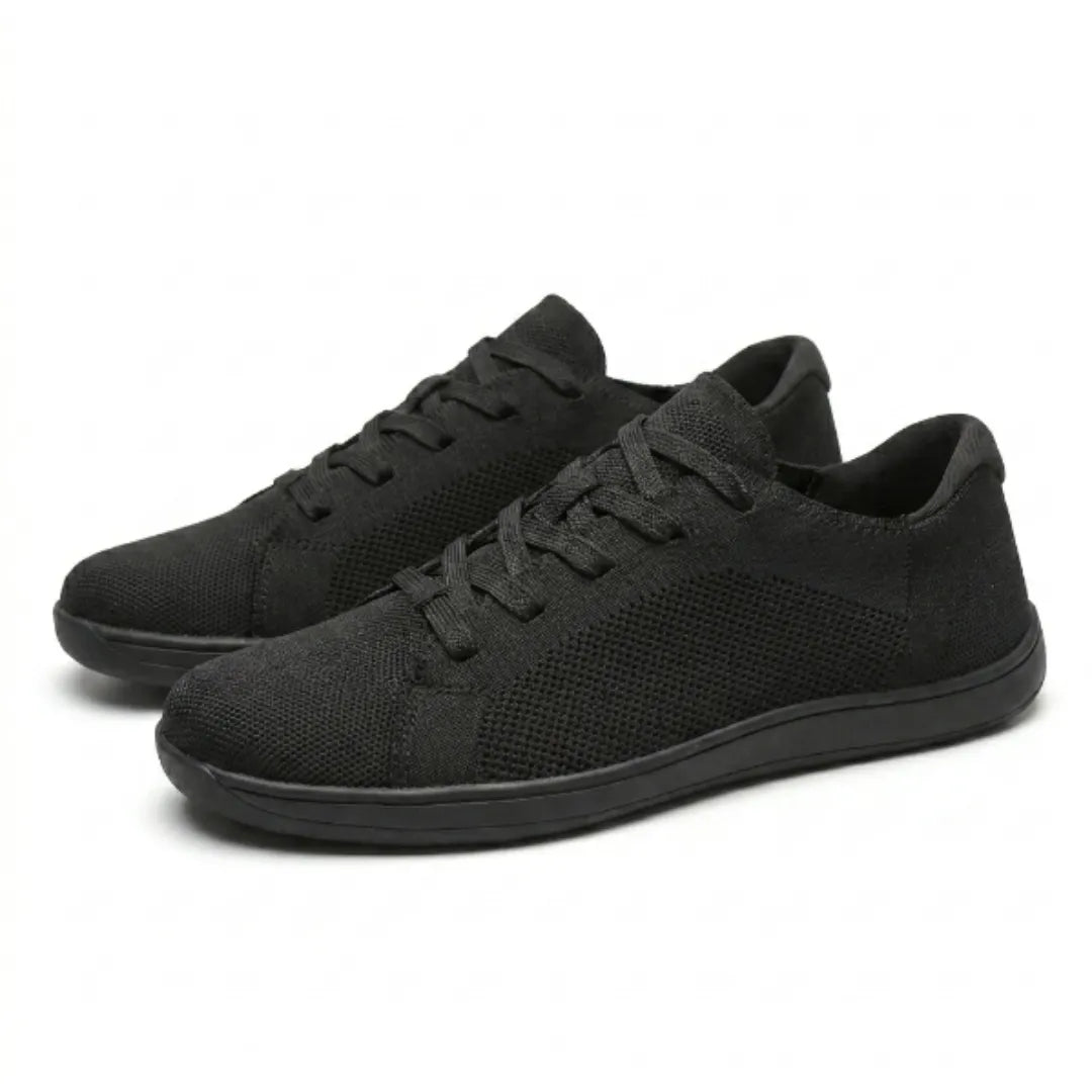 Pair of black knit trainers angled together, showing laces, mesh side panels and flat black soles. 16