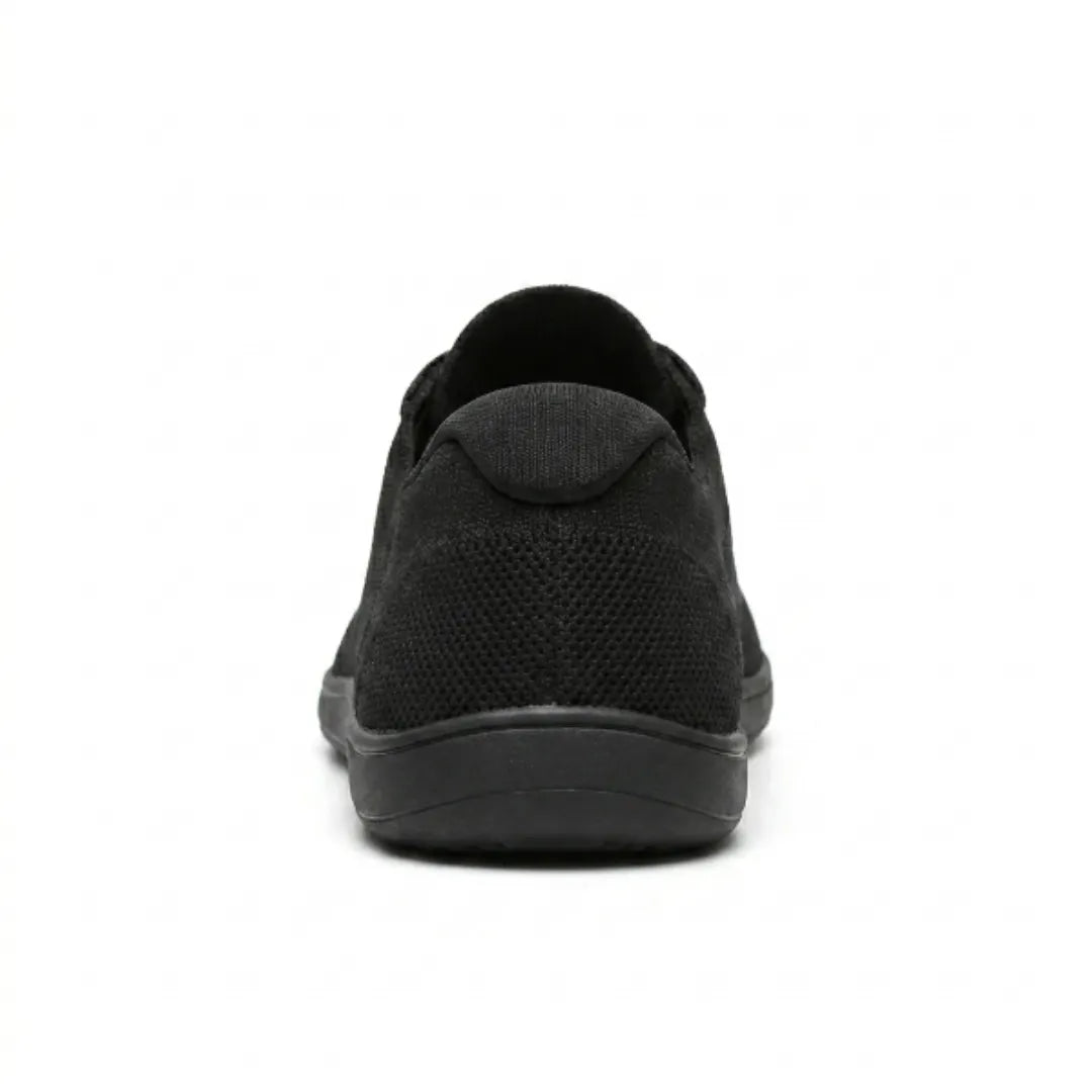 Rear view of a black knit trainer showing the heel tab, perforated knit and flat sole. 18