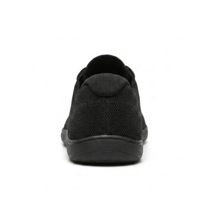 Rear view of a black knit trainer showing the heel tab, perforated knit and flat sole. 18
