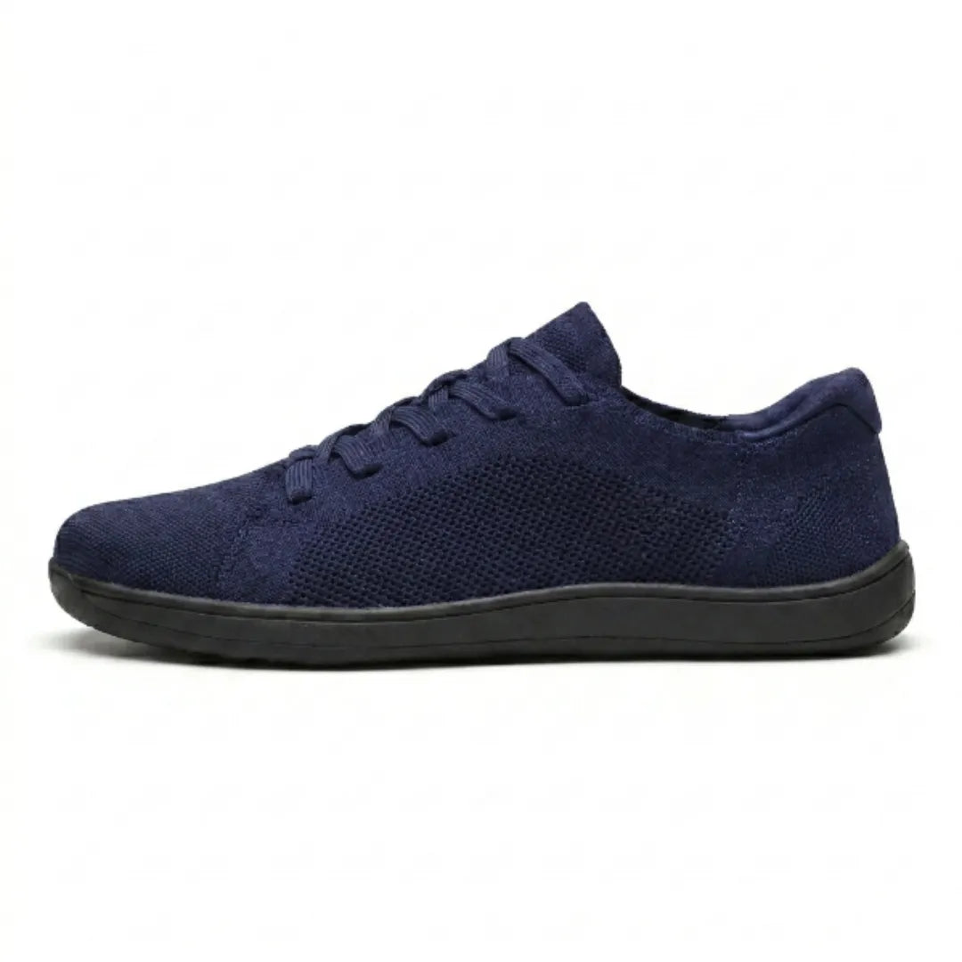 Side view of a navy blue knit trainer with a perforated mesh panel and a flat black sole. 19