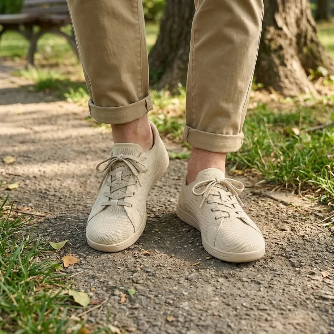 Beige trainers worn with rolled khaki trousers on a park path, shown on feet from the front. 2
