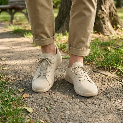 Beige trainers worn with rolled khaki trousers on a park path, shown on feet from the front. 2
