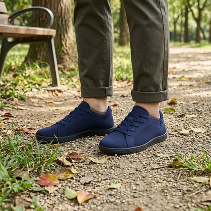 Navy blue trainers with black soles worn with rolled olive trousers beside a park bench. 20